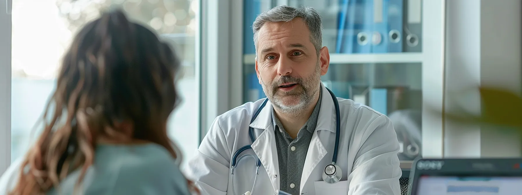 a doctor having a focused conversation with a patient while a medical ai scribe takes notes.